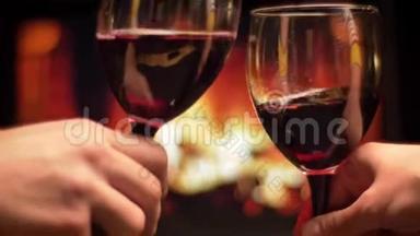 亲密拍摄两只手的朋友<strong>碰杯红酒</strong>庆祝与舒适温暖的壁炉上